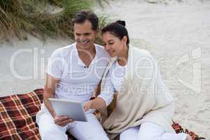 Happy couple using digital tablet on beach