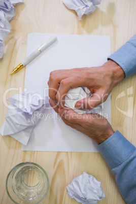 Close-up of graphic designer crumpling paper at his desk