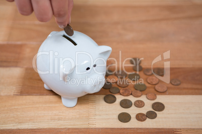 Hand inserting a coin into the piggy bank
