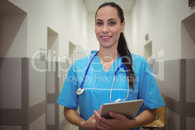 Portrait of female surgeon using digital tablet in corridor