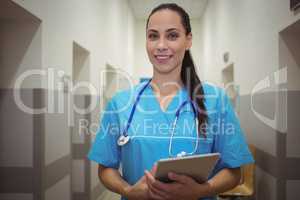 Portrait of female surgeon using digital tablet in corridor