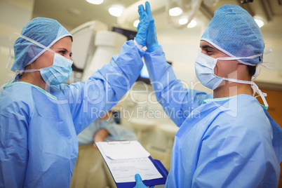Male and female surgeon giving high-five to each other