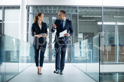 Business colleagues interacting with each other while walking in the corridor