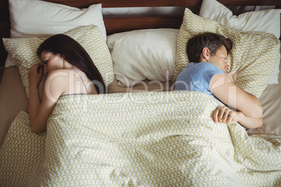 Couple sleeping back to back and ignoring each other on bed