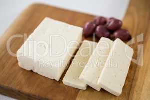 Cheese with olives on wooden board