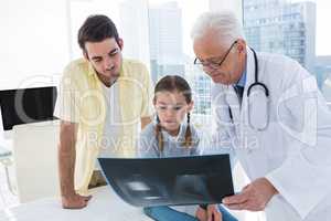 Doctor discussing x-ray report with father and daughter