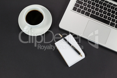 Cup of coffee, laptop, notepad and pen
