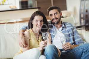 Happy couple relaxing on sofa and holding glasses of champagne
