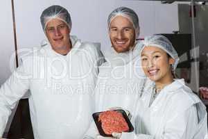 Butcher holding raw meat patties arranged in tray