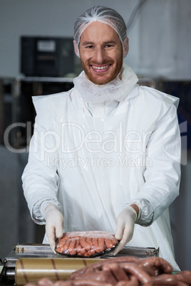 Male butcher weighing sausages at meat factory