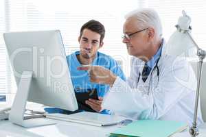 Surgeon and doctor discussing over personal computer