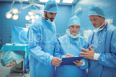 Male and female surgeon discussing over clipboard in operation theater