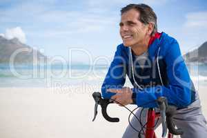 Smiling man leaning on bicycle