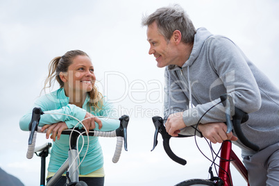 Couple leaning on bicycle while interacting with each other