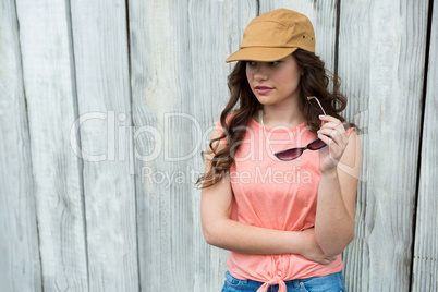 Woman in brown cap holding sunglasses