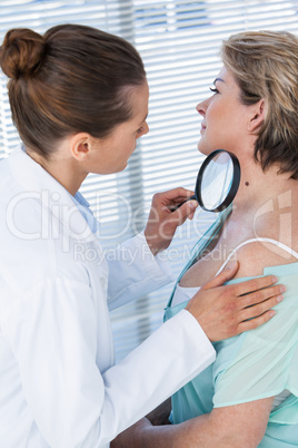 Dermatologist examining mole with magnifying glass