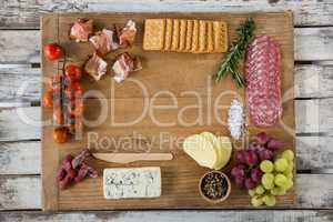 Roquefort cheese, biscuits and ham with various ingredients on chopping board