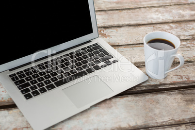 Cup of coffee and laptop on wooden table