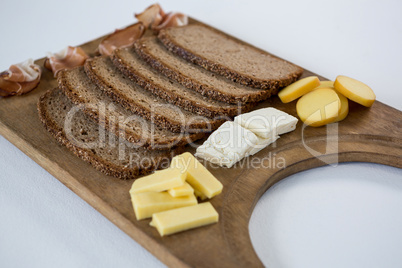 Variety of cheese with brown bread on wooden board