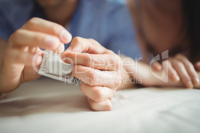 Close-up of couple with a condom on bed