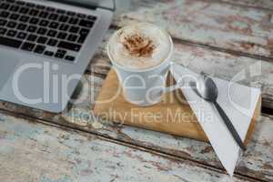 Cup of coffee and spoon with laptop