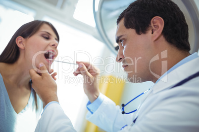 Doctor examining female patients mouth