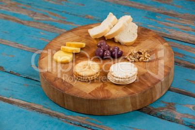 Cheese, bread, olives, biscuits and walnut on wooden board