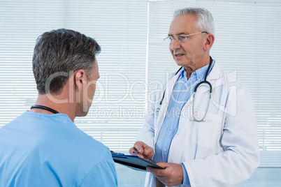 Doctor and surgeon discussing over clipboard