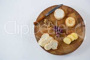 Slices of bread, crackers, olives, walnut and knife on wooden board