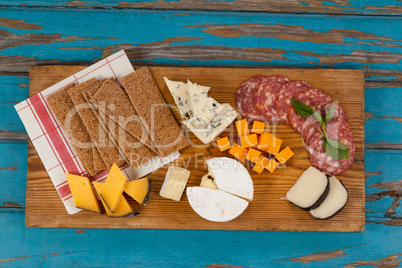 Cheese with ham and crispy biscuits on chopping board