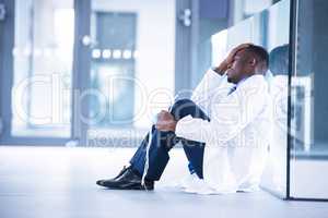 Worried doctor sitting on floor