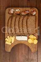Slices of brown bread, meat and cheese on wooden chopping board