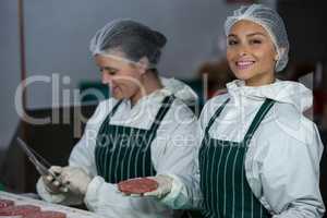 Female butchers maintaining records over digital tablet