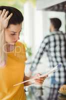 Tensed woman checking bill in kitchen