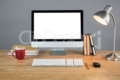 Books, table lamp and desktop pc on table
