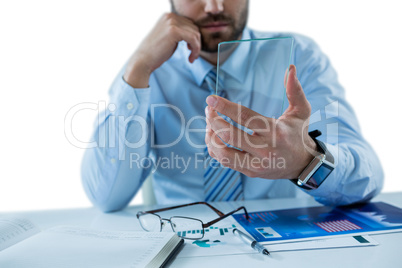Businessman sitting at table holding a glass sheet