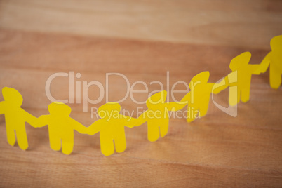 Paper cut outs forming a human chain on wooden table