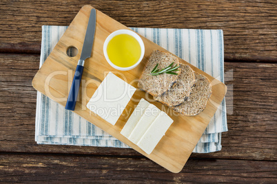 Gouda cheese, brown bread slices and lime juice with knife on chopping board