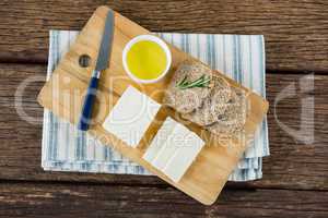 Gouda cheese, brown bread slices and lime juice with knife on chopping board