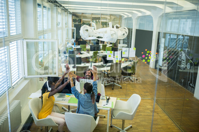 Team of business executives giving high five at desk