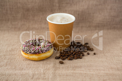 Doughnut, coffee beans and coffee on flax background