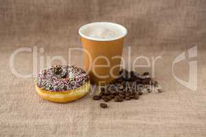 Doughnut, coffee beans and coffee on flax background