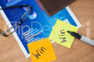 Win written on sticky note with marker spectacles and graph