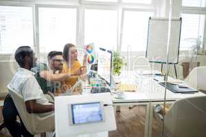 Graphic designers discussing over computer at their desk