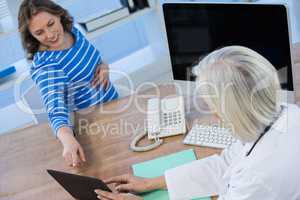 Doctor discussing with pregnant patient over digital tablet