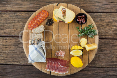 Gouda cheese, sweet lime, meat, bread slices, black pepper and rosemary on wooden board