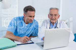 Surgeon and doctor discussing over laptop