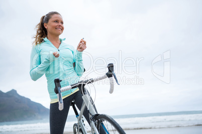 Happy woman standing with bicycle on beach