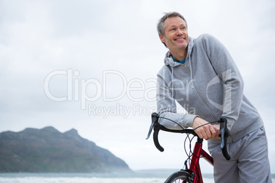 Happy man leaning on bicycle at beach