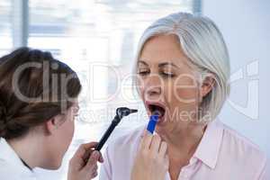 Doctor examining patients teeth with otoscope